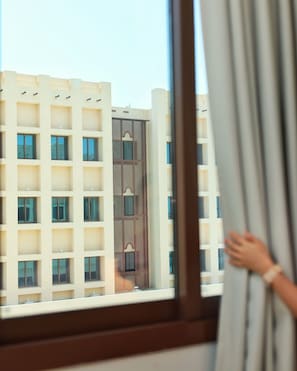 A view of a building with multiple balconies and a patterned facade through a window.