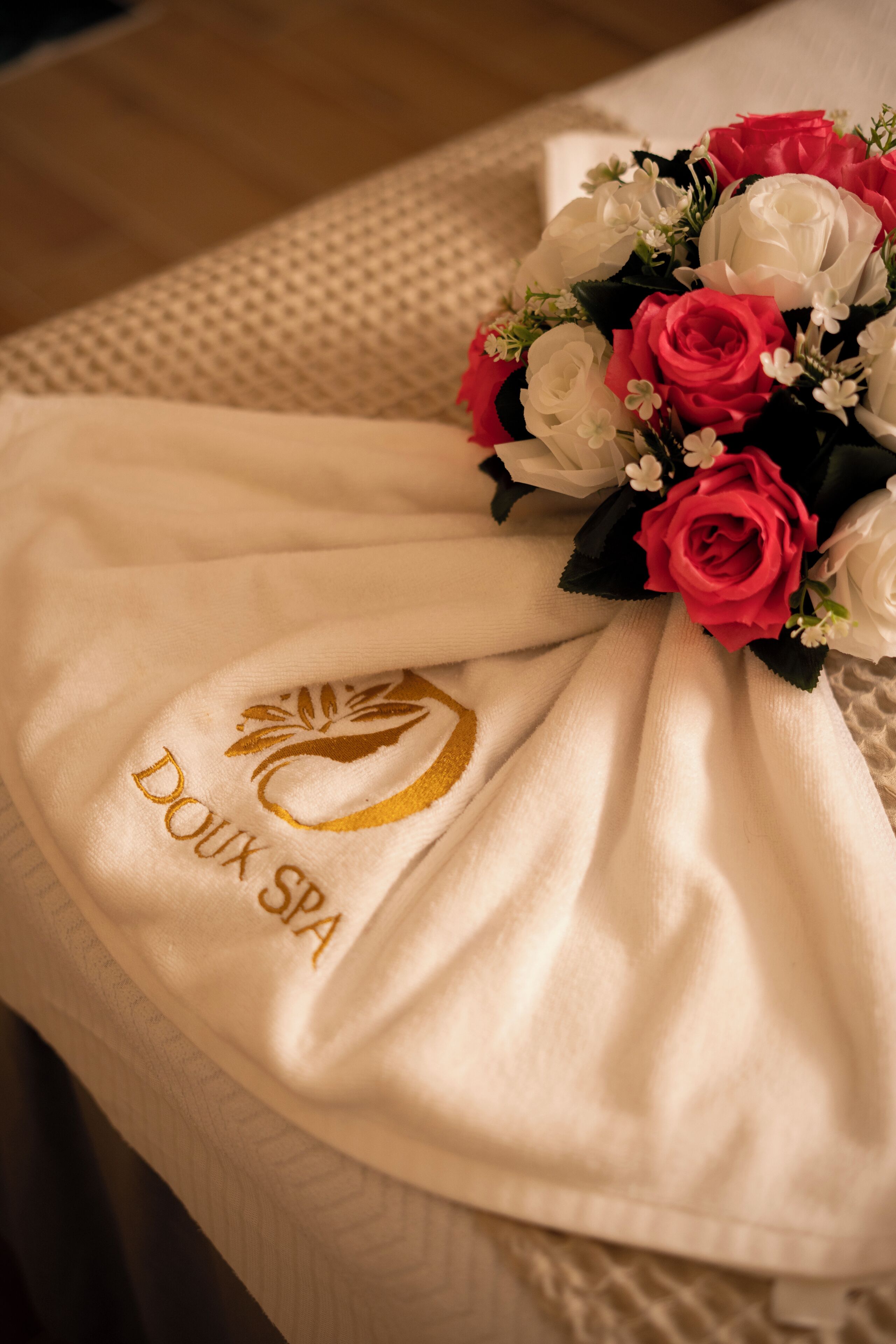 A bed with a white towel and a bouquet of flowers.