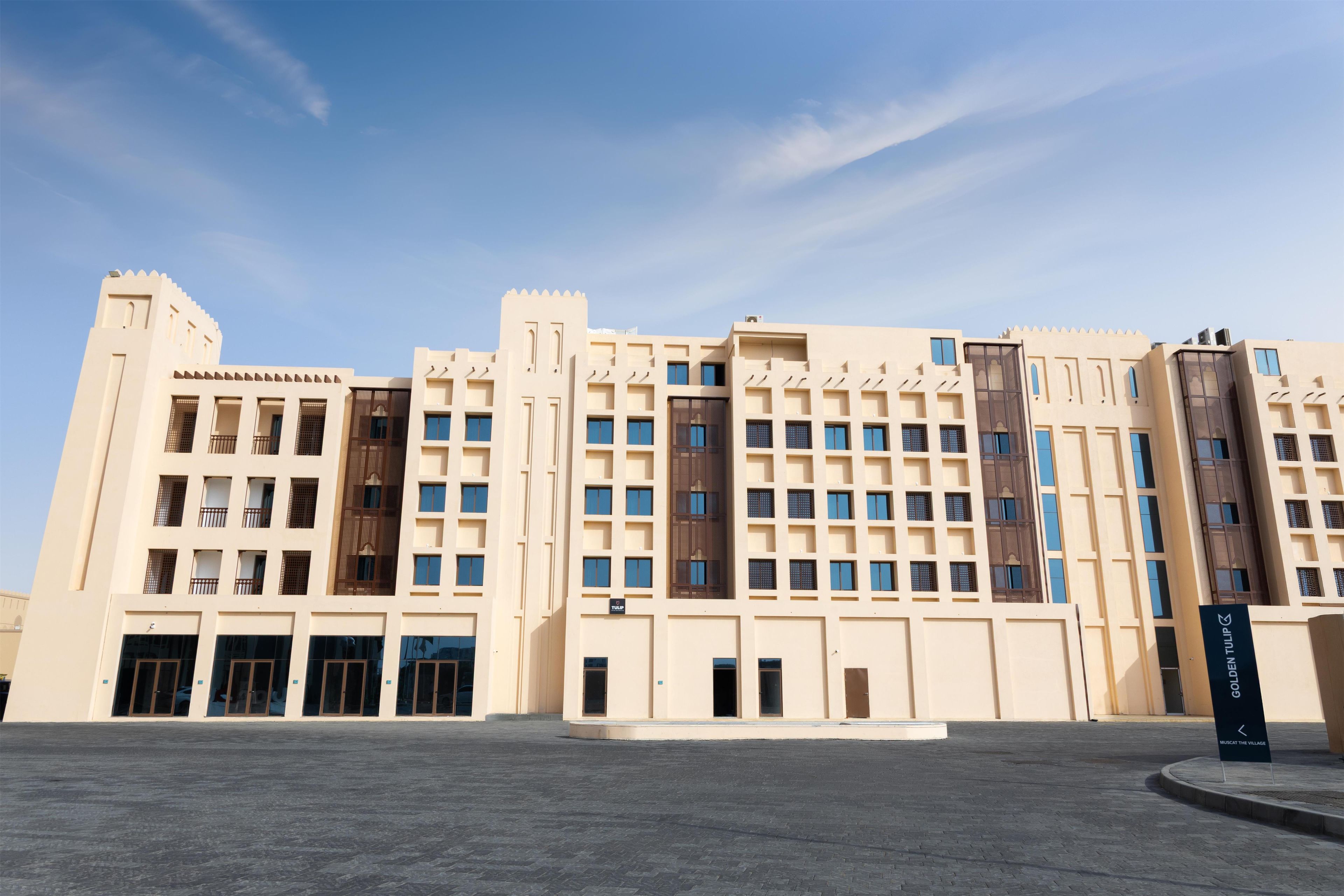 A large, multi-story building with a symmetrical facade, featuring a central entrance and multiple windows.