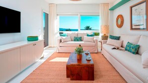 A living room with a large window, a flat-screen TV, a wooden coffee table, and a sofa. - Beachfront Apartment in Puerto Banus Playa Rocio (Marbella)