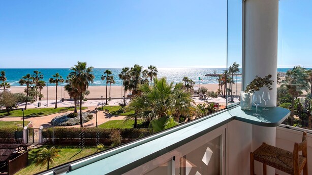 A balcony with a view of the beach, palm trees, and a clear sky. - Beachfront Apartment in Puerto Banus Playa Rocio (Marbella)