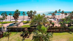 A coastal view with palm trees, a beach, and a clear sky. - Beachfront Apartment in Puerto Banus Playa Rocio (Marbella)