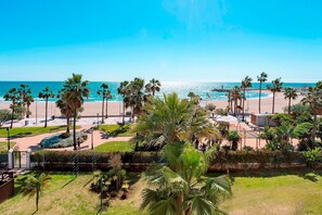 Blick auf die Küste mit Palmen, einem Strand und blauem Himmel.