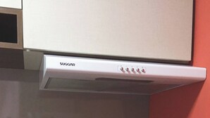 Keittiössä on valkoinen liesituuletin, musta induktioliesi ja graniittitaso.