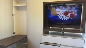 Television on asennettu kaappiin, jonka alla on puinen hylly.