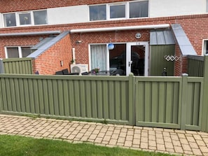 A residential building with a brick facade, a green fence, and a sliding glass door entrance. - 4 Star Holiday Home in Hemmet (Hemmet)