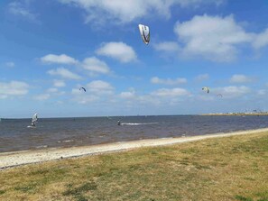 A beach with a clear sky, a sandy shore, and a few people windsurfing. - 4 Star Holiday Home in Hemmet (Hemmet)