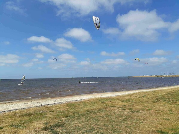 A beach with a clear sky, a sandy shore, and a few people windsurfing. - 4 Star Holiday Home in Hemmet (Hemmet)