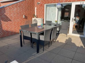 An outdoor patio with a table and chairs, a brick wall, a sliding glass door, and a Panasonic air conditioning unit. - 4 Star Holiday Home in Hemmet (Hemmet)