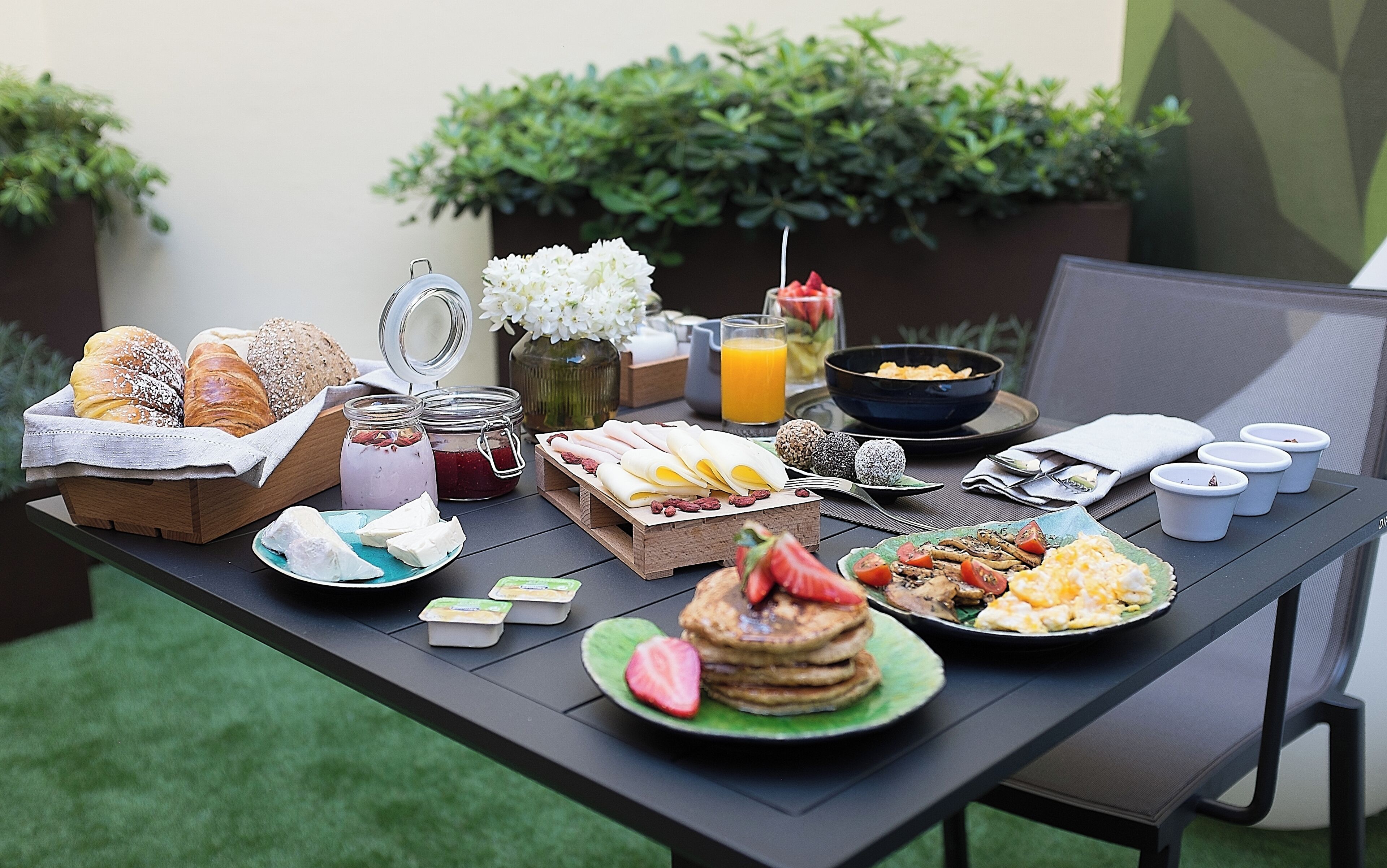 A breakfast table with various food items, including pastries, fruits, and beverages.
