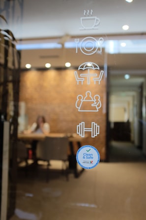 Vista borrosa del interior de un restaurante con iconos que muestran servicios como café, mesas, sombrillas y un espacio para entrenamiento físico.