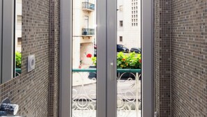A bathroom with a sink, a mirror, and a view of a street through a door. - OMID Boutique (Lisbon)