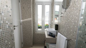 A bathroom with mosaic tile walls, a window, a sink, and a toilet. - OMID Boutique (Lisbon)