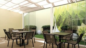 A modern indoor dining area with glass walls, a table, and chairs. - OMID Boutique (Lisbon)