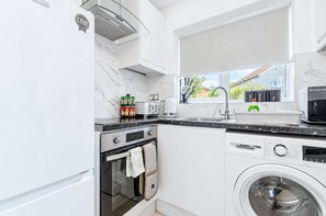 Une cuisine moderne équipée d’un four encastré, d’un four à micro-ondes et d’un lave-linge.