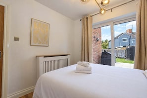 Une chambre à coucher avec un lit, un radiateur, une fenêtre avec des rideaux et une vue sur l’extérieur.