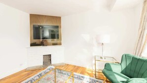 Un salon moderne avec une cheminée, un canapé vert et un tapis à motifs.