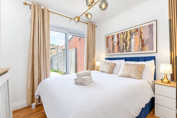 Une chambre d’hôtel avec un grand lit, une vue sur l’extérieur et un tableau au mur.