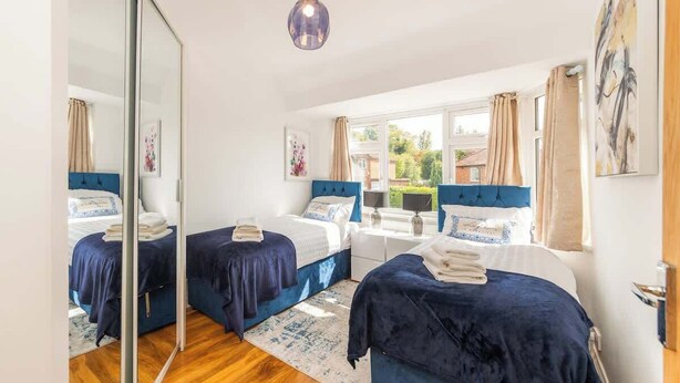 Une chambre avec deux lits, un miroir, un bureau et une vue sur l’extérieur.