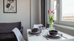 Ett matbord dukat med tallrikar, skålar, glas och bestick, en vas med blommor och ett inramat konstverk på väggen.