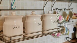 Küchenregale mit Aufbewahrungsbehältern, beschriftet mit 'Zucker', 'Tee' und 'Kaffee'.