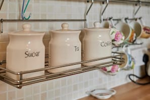 Kitchen storage shelves with containers labeled 'Sugar,' 'Tea,' and 'Coffee.' - Host & Stay | The Garden Flat, Seahouses (Seahouses)
