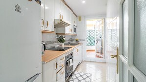 Een keuken met witte kasten, een houten aanrecht, een fornuis en een spoelbak.