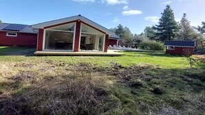 A modern house with a glass front, a red exterior, and a sloped roof. - 4 Star Holiday Home in Romo (Rømø)