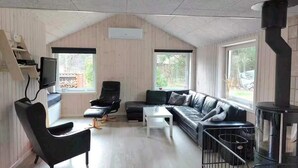 A modern living room with a sofa, a chair, a coffee table, a TV, and a fireplace. - 4 Star Holiday Home in Romo (Rømø)
