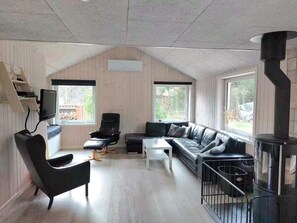 Ein modernes Wohnzimmer mit einer Couch, einem Sessel, einem Couchtisch, einem Fernseher und einem Kamin.