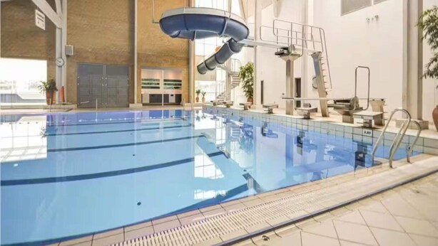 An indoor swimming pool with diving platforms, a lifeguard chair, and a clear view of the pool's edge. - 4 Star Holiday Home in Romo (Rømø)