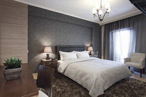 A bedroom with a bed, two bedside tables, a lamp, a chair, and a potted plant.