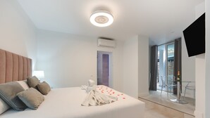 Une chambre d’hôtel moderne dotée d’un grand lit, d’une télévision à écran plat et d’une porte vitrée donnant sur un balcon.