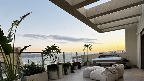 Terraza en la azotea con plantas en macetas, asientos y vista al mar.