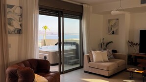 Una sala moderna con un sofá de cuero marrón, un sofá blanco y un comedor con mesa y sillas.