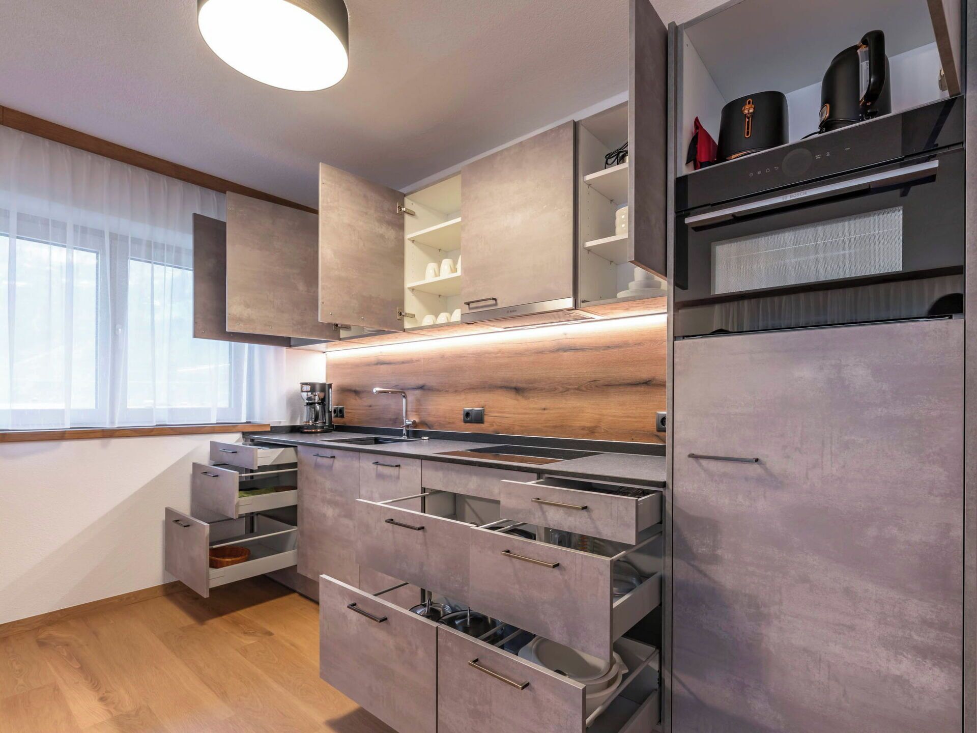 Eine moderne Küche mit eingebauten Geräten, Holz Arbeitsplatten und einem Fenster mit leichtem Vorhang.