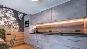 Eine moderne Küche mit grauen Schränken, einer Holz Arbeitsplatte und einem eingebauten Ofen.