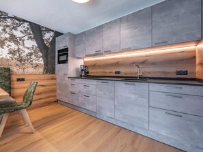 Eine moderne Küche mit grauen Schränken, einer Holz Arbeitsplatte und einem eingebauten Ofen.