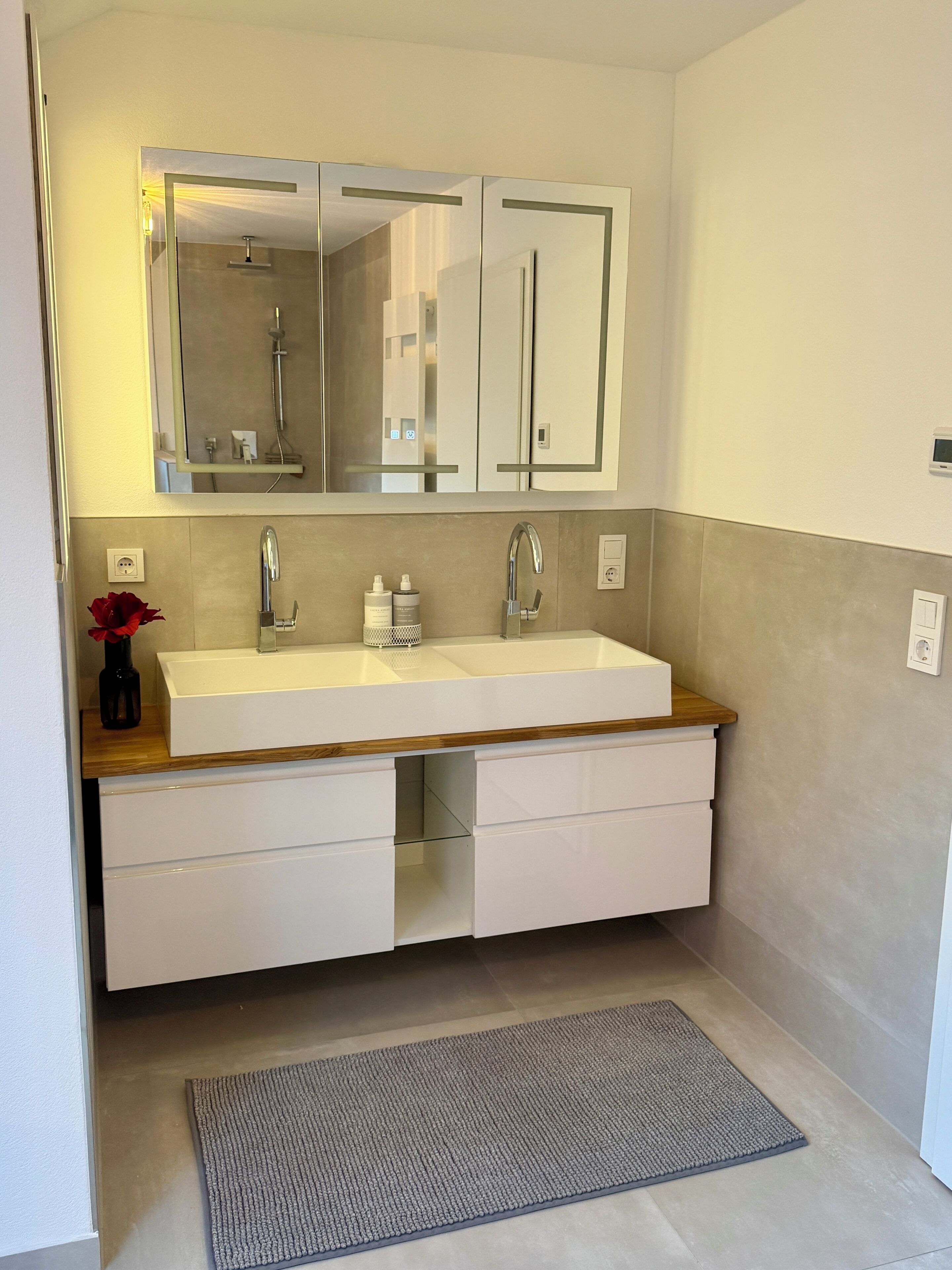 Un baño con lavamanos doble, un espejo y una encimera de madera.