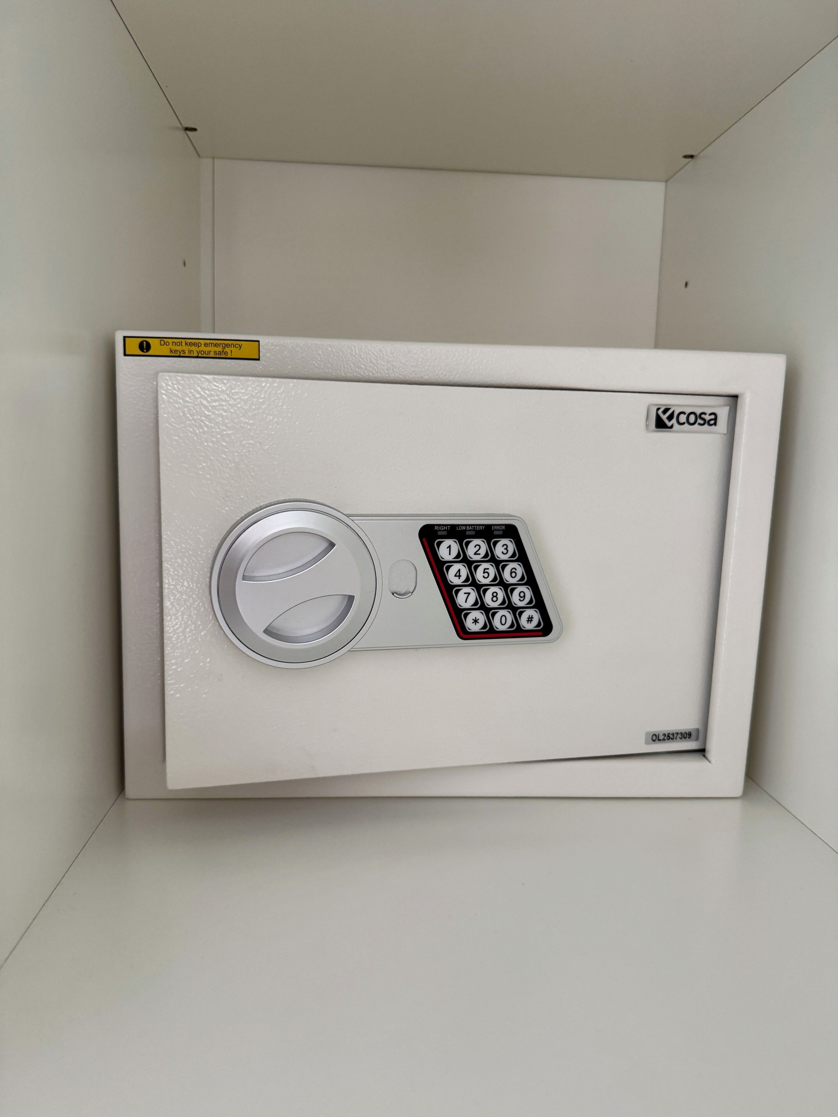 A white safe with a numeric keypad and a circular lock mechanism, labeled 'cosa' and 'OL2637309'.