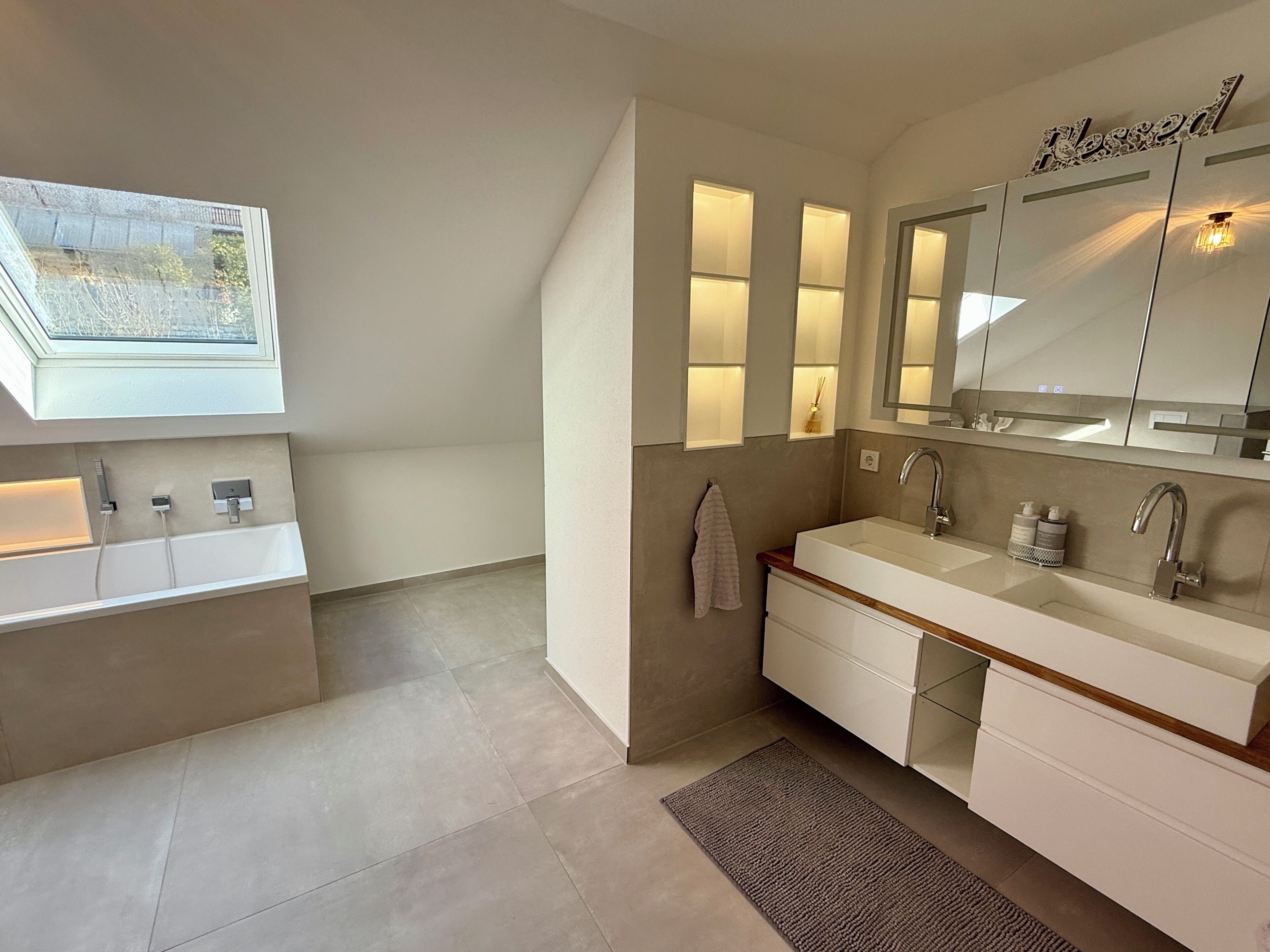 Une salle de bain moderne dotée d’un puits de lumière, d’un grand miroir et d’un lavabo encastré.
