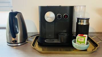 Een Nespresso koffiemachine op een dienblad met een koffiekannetje, een thermoskan en een mok.