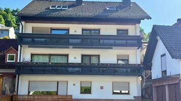 Ein zweistöckiges Wohnhaus mit Balkon, Garage und einem sichtbaren Schornstein.