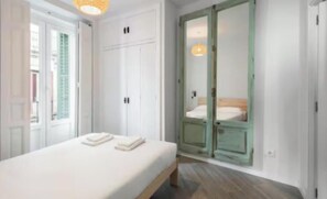 A bedroom with a bed, a wardrobe, and a mirror. - Spacious & Bright 4-Bedroom Apartment in Central Madrid (Madrid)