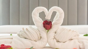 A bed with a white headboard, a heart-shaped towel arrangement, a red rose, and scattered rose petals. - Valeria Room: Double Whirlpool Bath, Mountain Views (Carratraca)