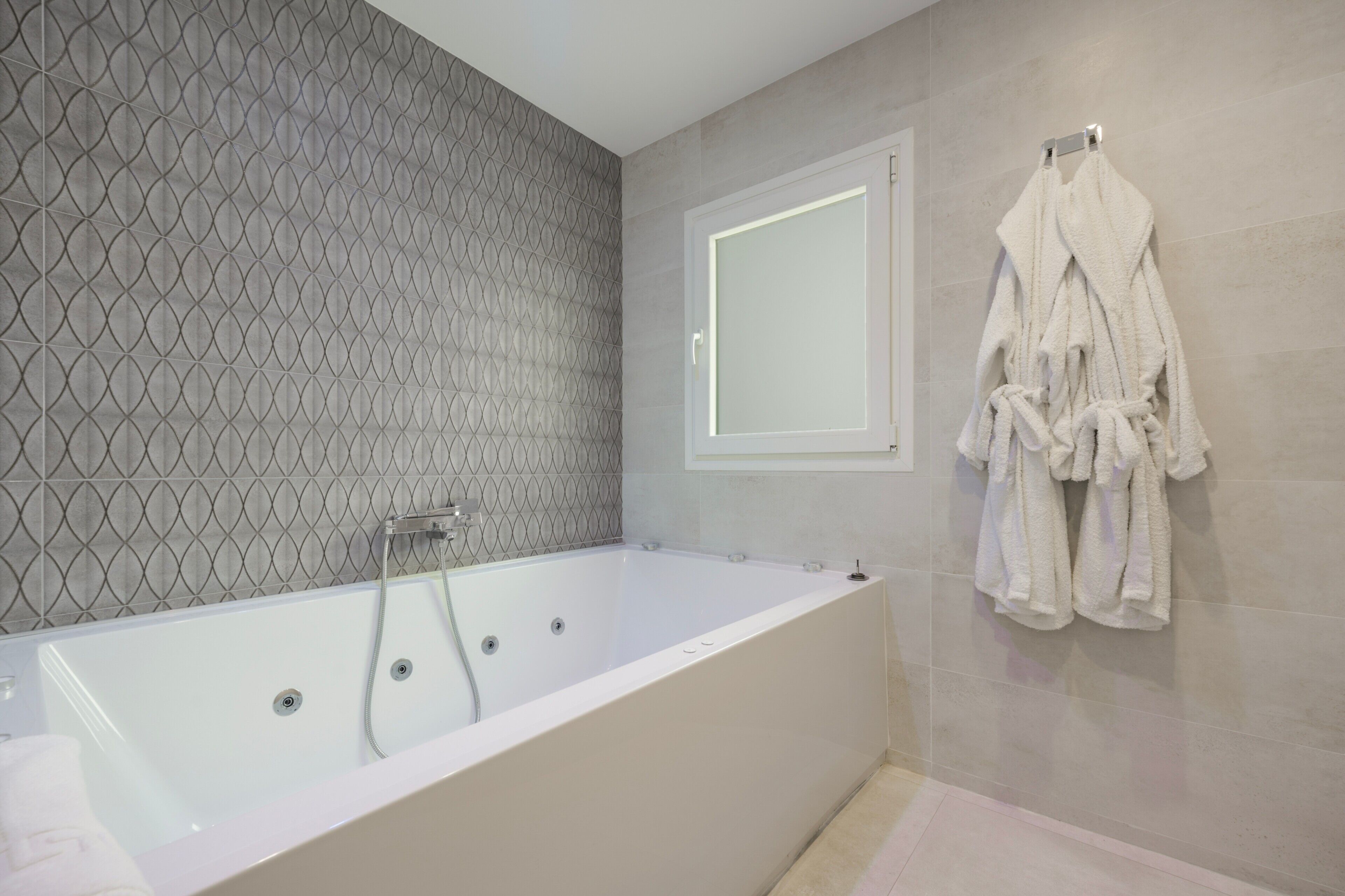 Une salle de bain moderne équipée d’une baignoire, d’une douche et d’un porte-serviettes avec des peignoirs.