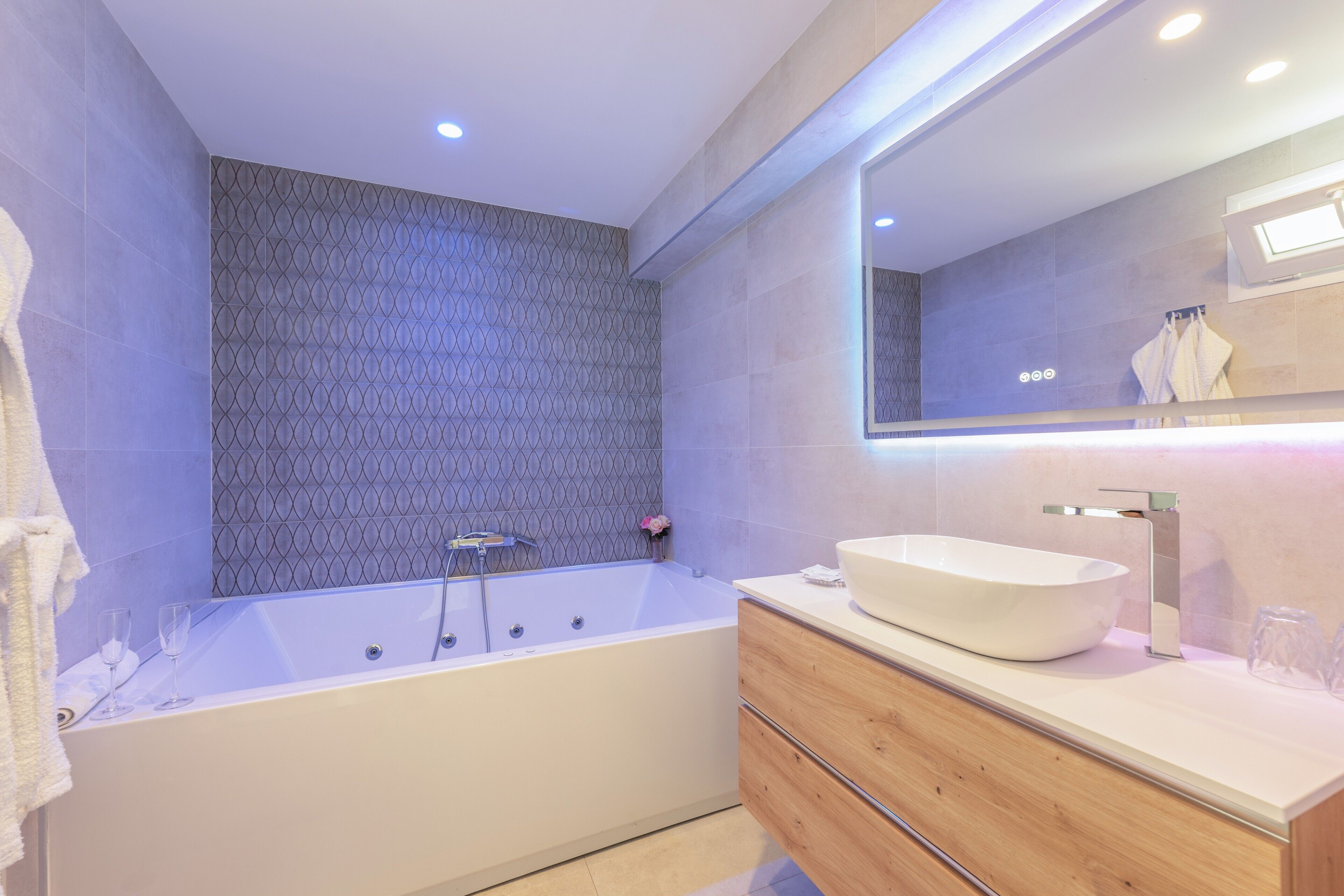 Un baño moderno con una bañera independiente, un tocador de madera y un espejo grande.