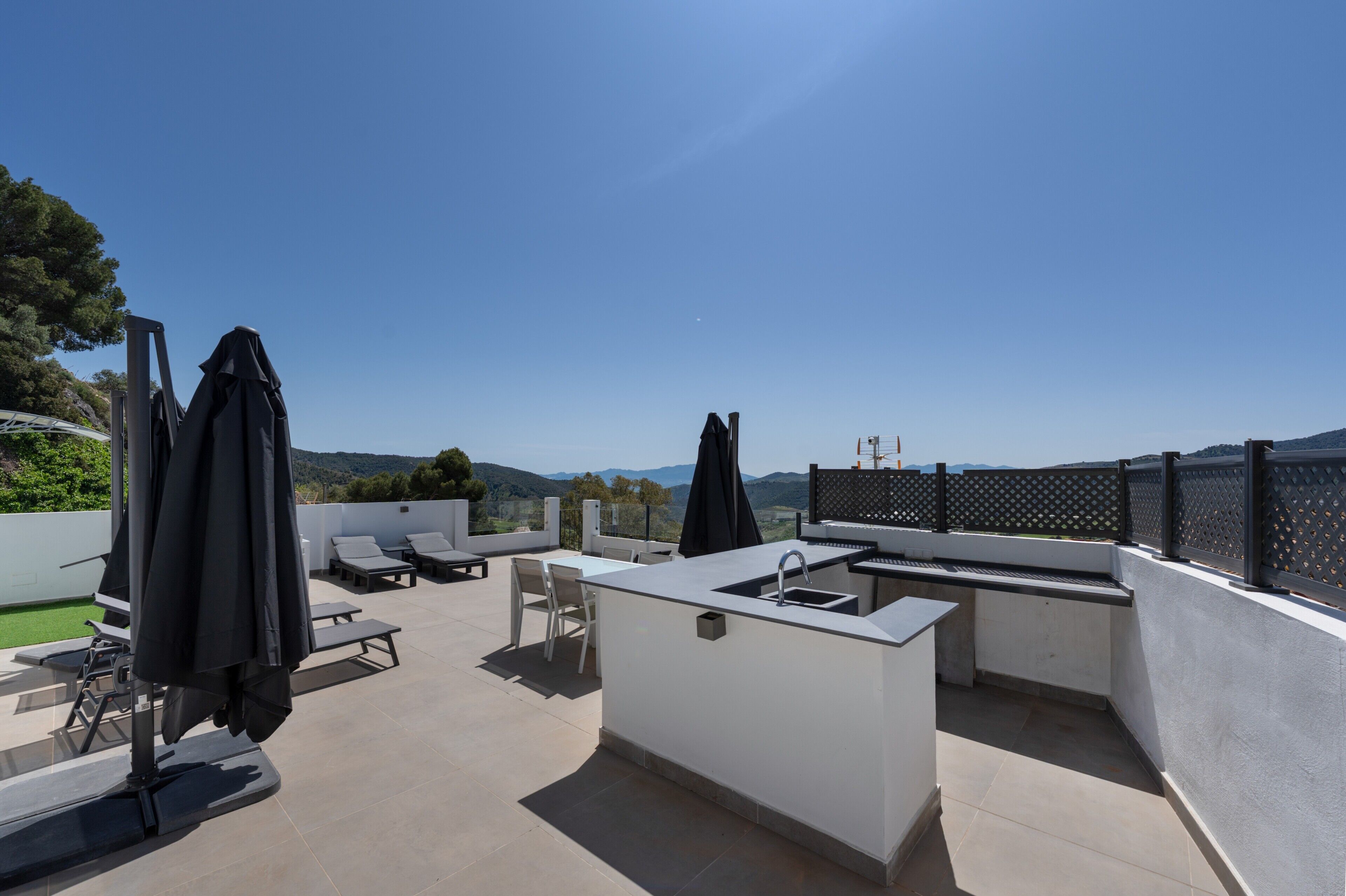 Terraza exterior con zona de cocina, asientos y vistas a las colinas.