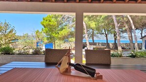 Un espacio al aire libre techado con una mesa, sillas y vista al mar.