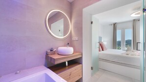 Ein modernes Badezimmer mit rundem Spiegel, Waschbecken und Badewanne.